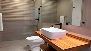 A modern bathroom with a wooden vanity, a white sink, and a toilet. - The Penthouse at Vista Alta (Punta Cana)