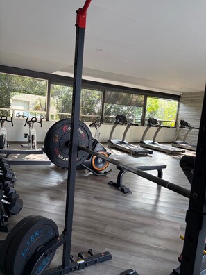 A gym with exercise equipment, large windows, and a view of greenery outside. - Panoramic view of the volcanoes, 1 hour from Taxco and 2.5 hours from the beach (Cuernavaca)