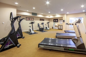 Une salle de sport équipée de tapis de course, de vélos d’appartement et d’appareils de musculation elliptique.