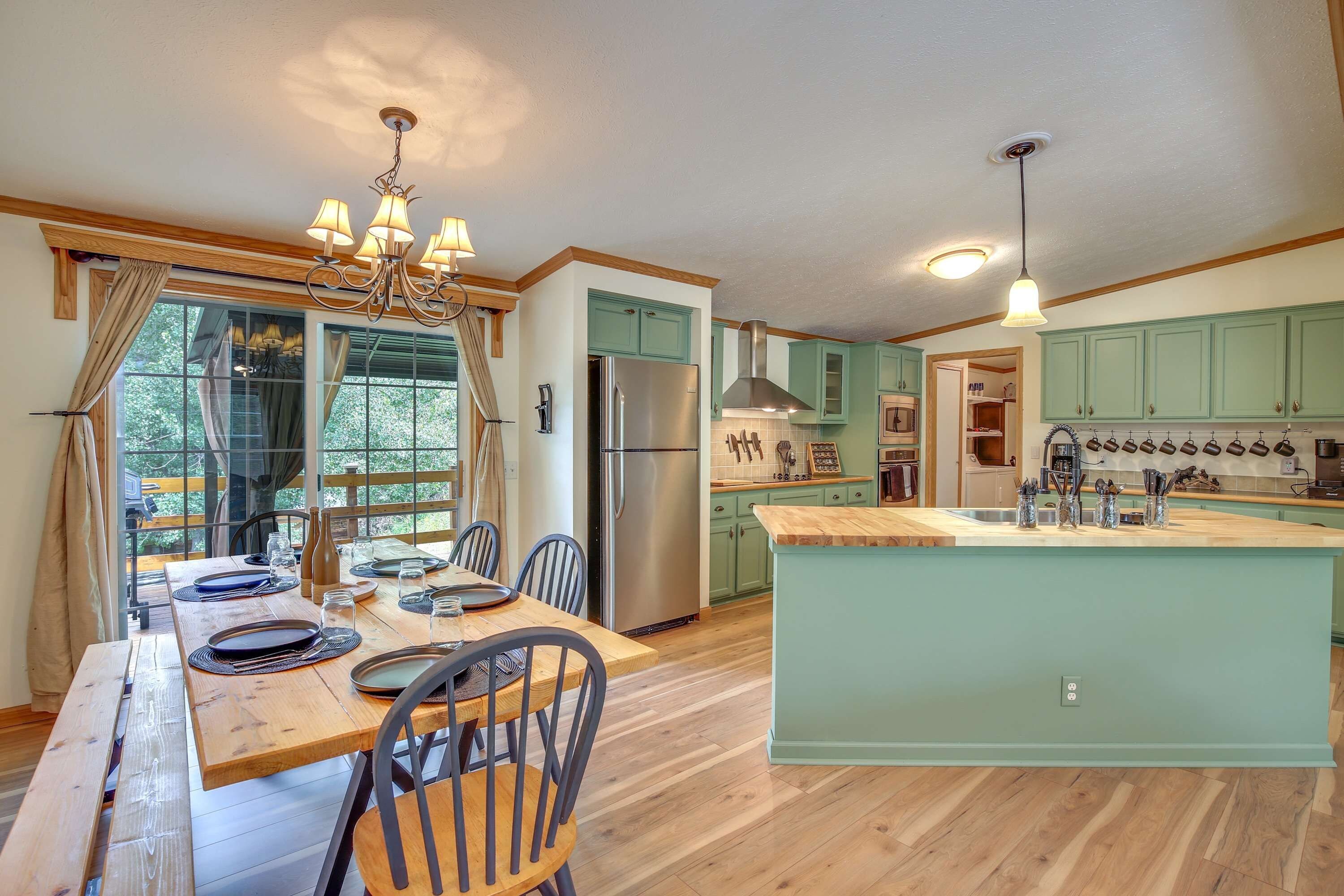 Una cocina moderna con una isla central, suelo de madera y un comedor con mesa preparada para cuatro.