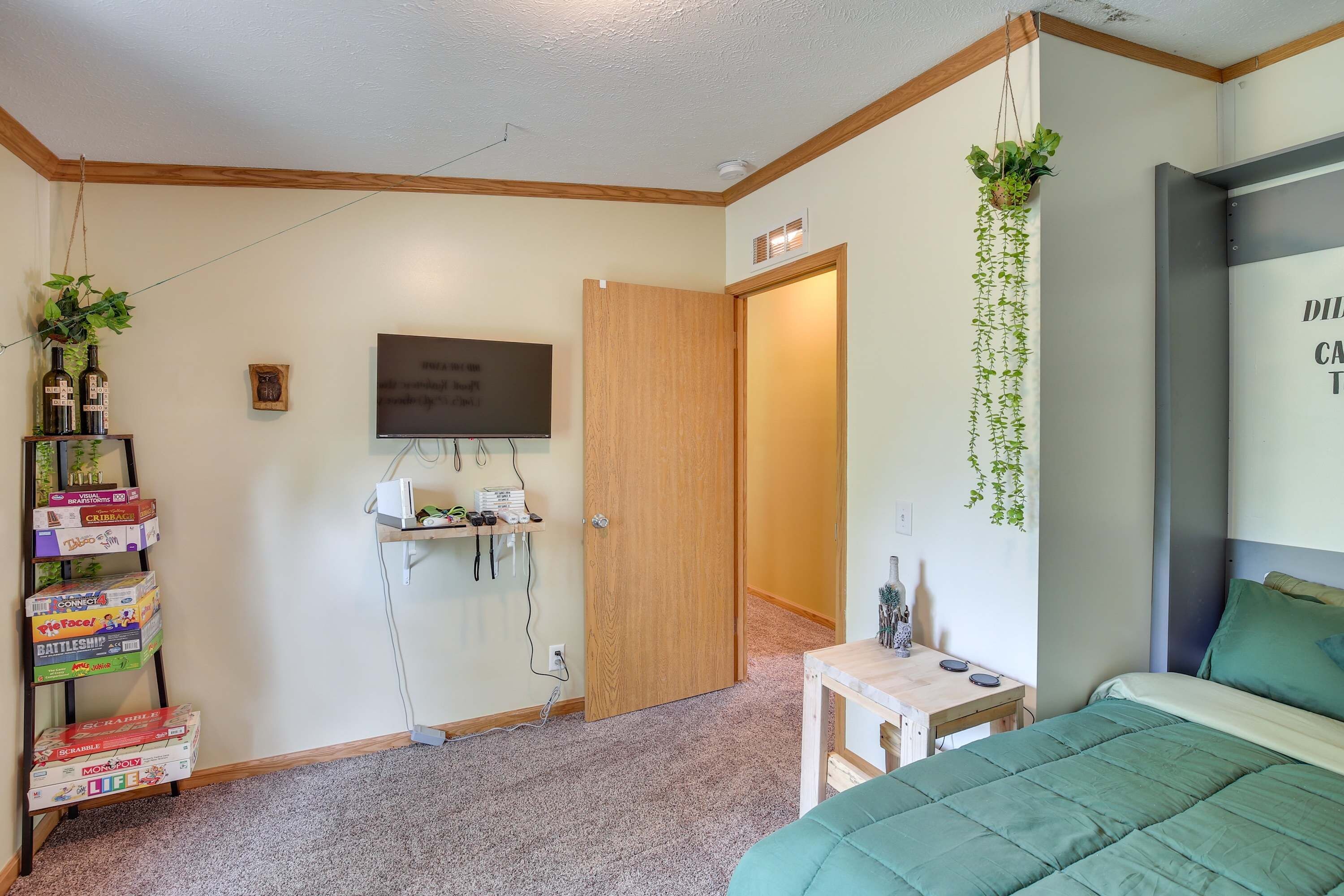 Un dormitorio con cama, escritorio, televisor y puerta que da a otra habitación.