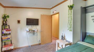 Un dormitorio con cama, escritorio, televisor y puerta que da a otra habitación.