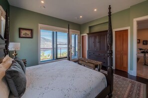 Ein Schlafzimmer mit einem großen Bett, einem Schminktisch, einer Bank und Blick ins Freie.