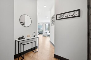 Ein Flur mit weißer Wand, einem runden Spiegel, einem schwarzen Bilderrahmen mit dem Wort 'blessed' und einem weißen Sofa im Hintergrund.