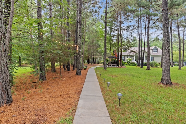 A pathway lined with trees and a house in the background.
