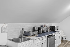 A modern kitchen with a stainless steel sink, a coffee maker, a microwave, and a dishwasher.