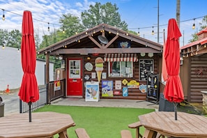 Een sfeervol ijssalon met een rode deur, terras en lichtjes.