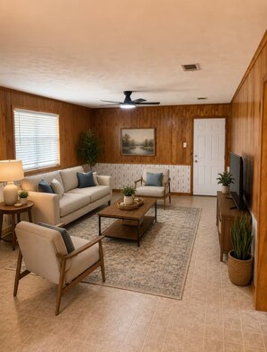 A living room with a sofa, armchair, coffee table, and a television. - Cozy Cottage- 5min from Data Center! (Boyce)