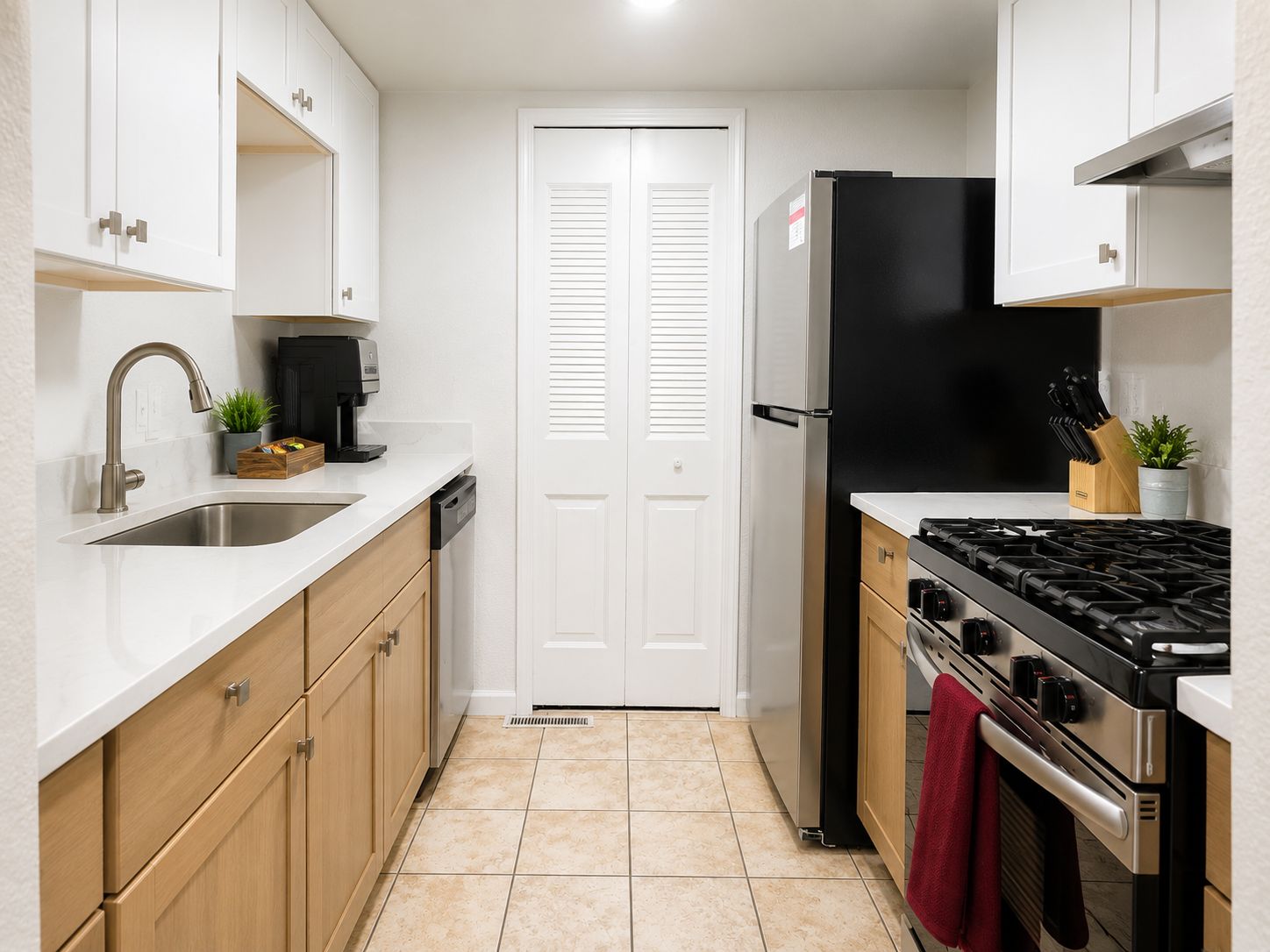 A compact kitchen with a stainless steel sink, a coffee machine, a black refrigerator, a stove, and wooden cabinets.