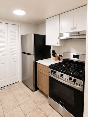A modern kitchen with a stainless steel refrigerator, a gas stove, and a built-in oven.