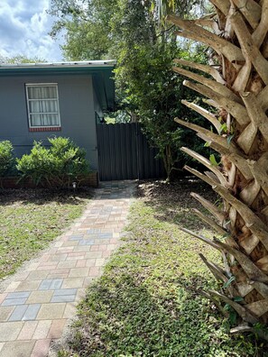Un chemin pavé mène à une maison dotée d’une fenêtre et d’une porte.