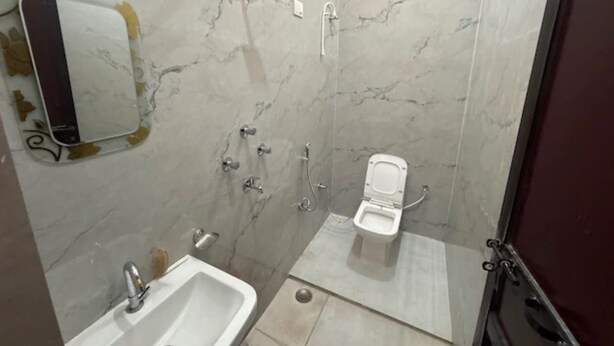 Une salle de bain avec un mur en marbre, un lavabo, des toilettes et une douche.