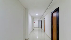 Un couloir bordé de portes des deux côtés, donnant accès à des pièces individuelles.