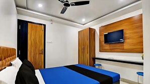 Une chambre d’hôtel équipée d’un lit, d’une armoire, d’un bureau et d’un téléviseur fixé au mur.