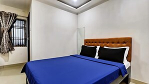 Une pièce avec un lit, une fenêtre avec des rideaux et un luminaire au plafond.