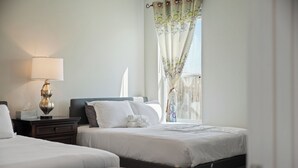 Une chambre d’hôtel avec deux lits, une table de chevet avec une lampe et une fenêtre avec des rideaux.