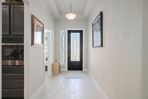 A hallway with a black door, framed artwork, and a built-in oven. - Katy Lake View Retreat - 4BR 3BATH w/ Arcade Games - King Bed (Katy)
