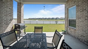 Une terrasse avec un barbecue, des chaises et une vue sur un quartier résidentiel.