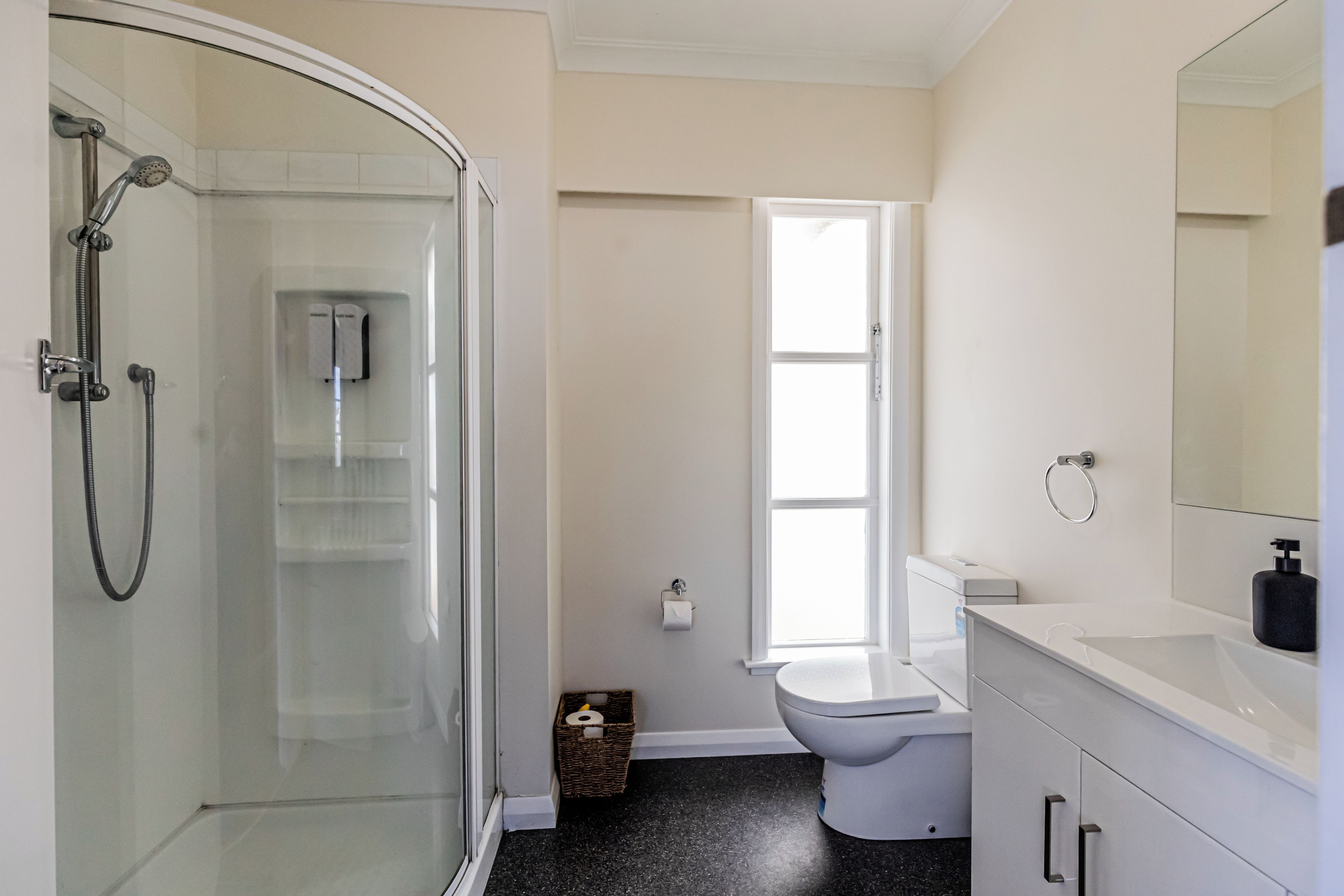 A bathroom with a glass-enclosed shower, a toilet, and a sink with a mirror.
