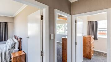A hotel room with a bed, a wooden nightstand, a wardrobe, and a window with curtains.