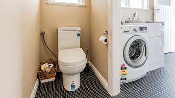 A compact bathroom with a toilet, a washing machine, and a small window.