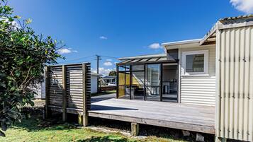 A modern mobile home with a deck, a glass door entrance, and a visible kitchen area.