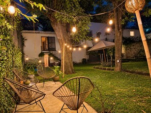 An outdoor seating area with wicker chairs and a string of lights. - Just 5 minutes from the archaeological site! Ideal family apartment with a garden (Malinalco)