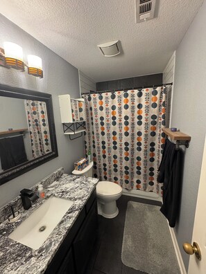 Ein Badezimmer mit Marmorwaschbecken, Toilette, einer Duschvorhang mit Punkten und einem Handtuchhalter.