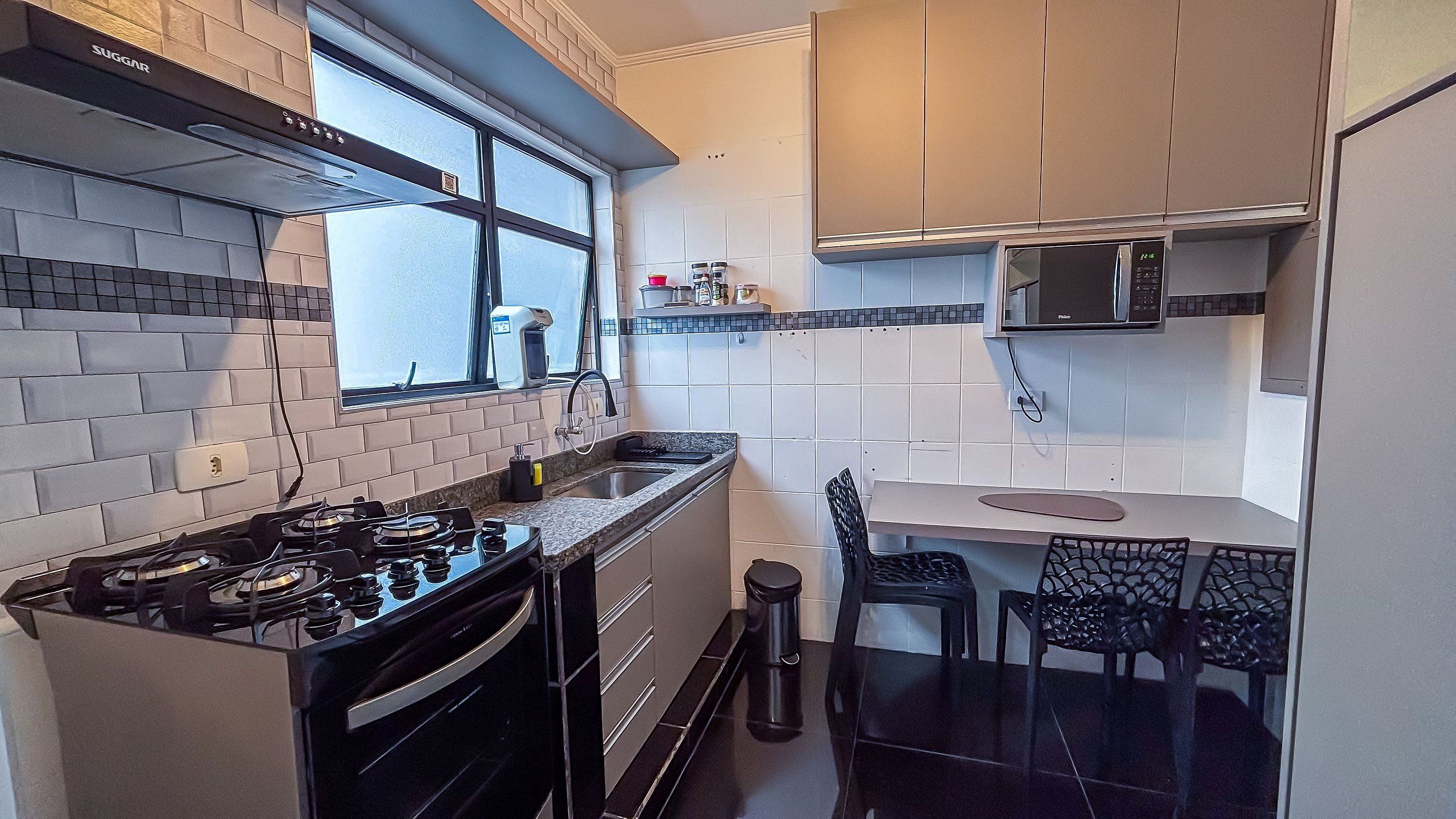 A compact kitchen with a gas stove, a microwave, and a window.