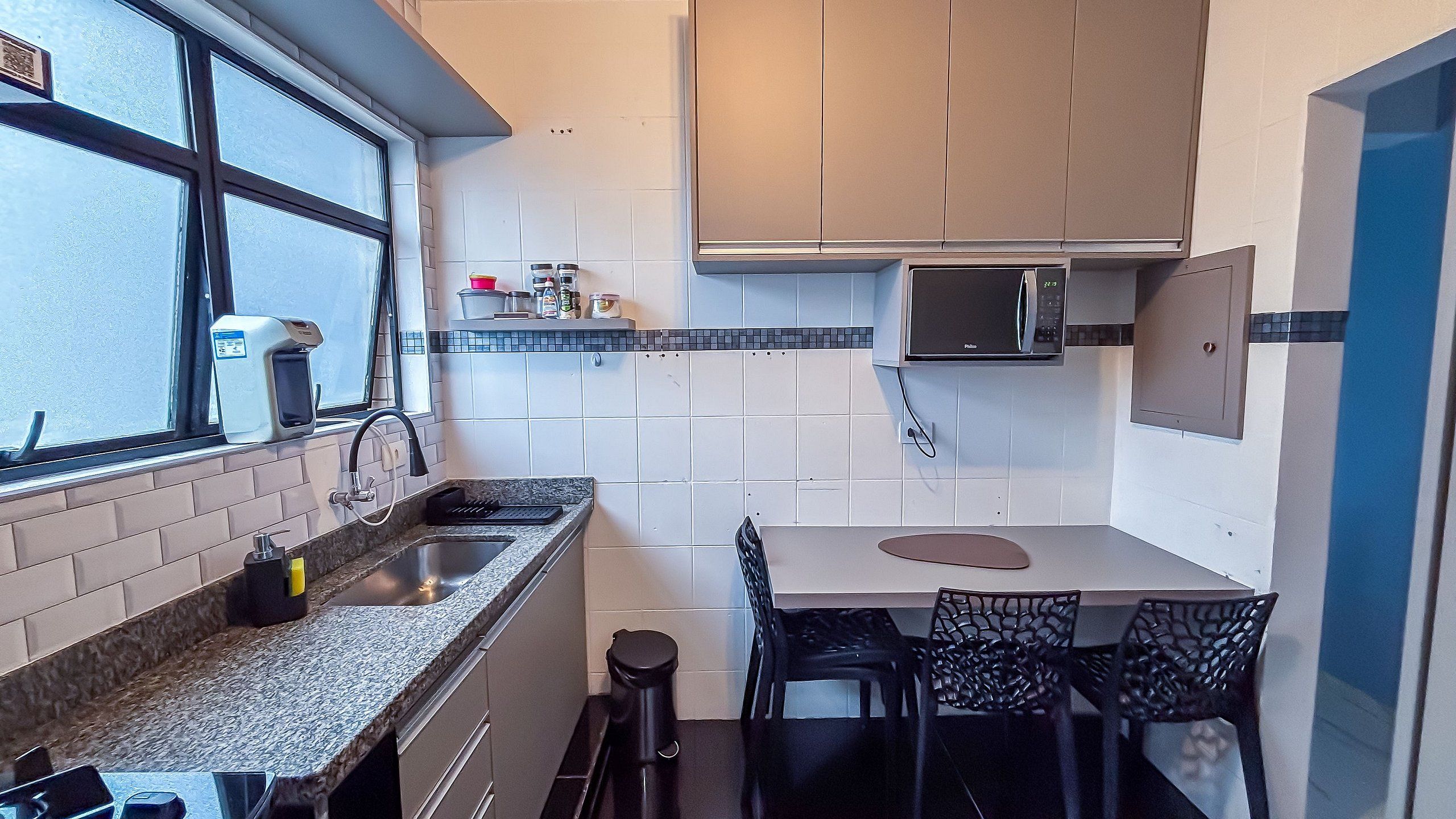 A compact kitchen with a window, a microwave, and a small dining area.