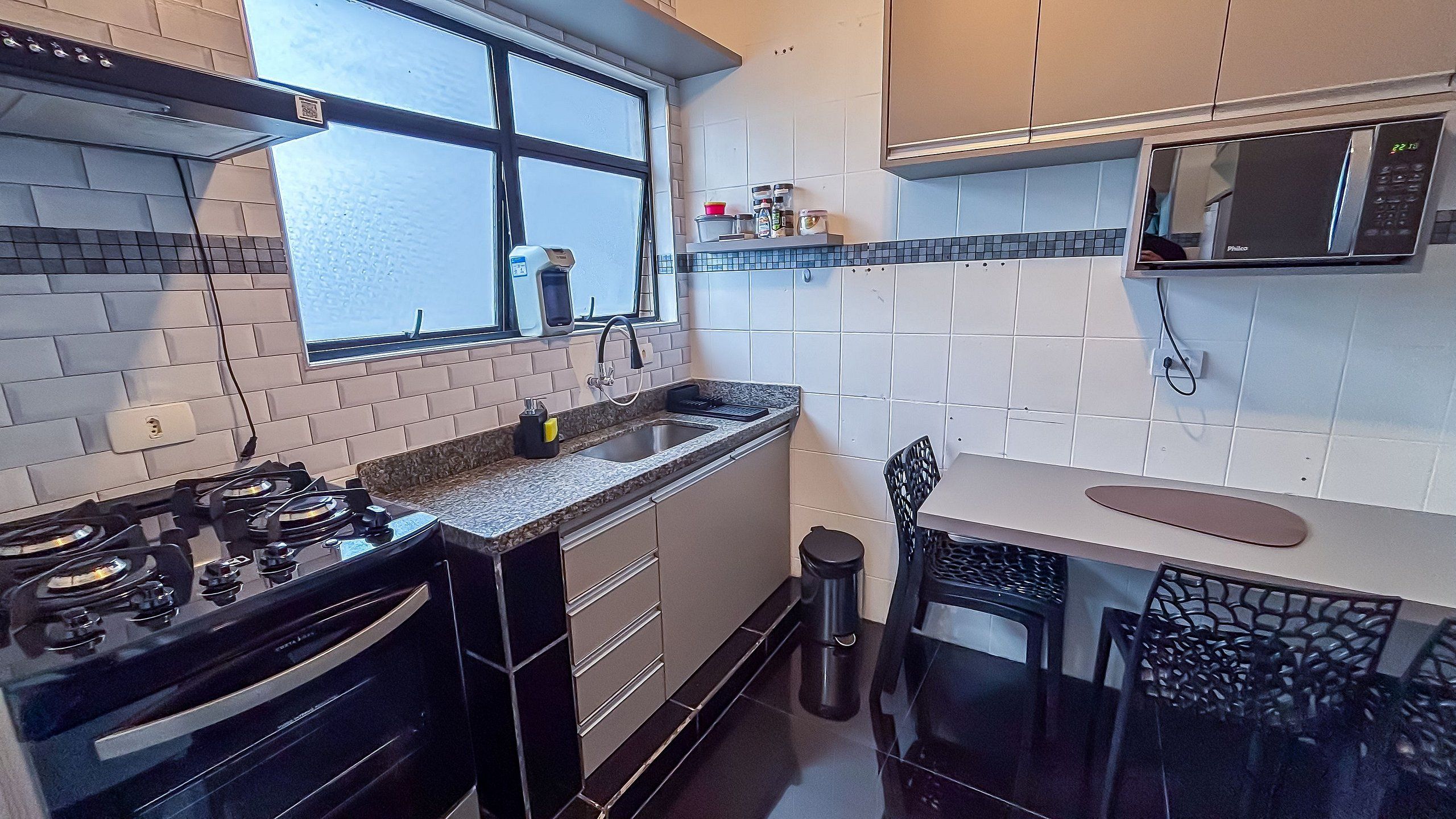A modern kitchen with a gas stove, a sink, a microwave, and a window.