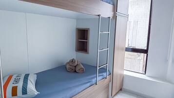 A bunk bed room with a window, a small shelf, and a tiled floor.
