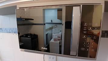 Uma cozinha com micro-ondas embutido, fogão a gás e pia.