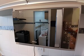 Una cocina con microondas integrado, estufa a gas y un lavamanos.