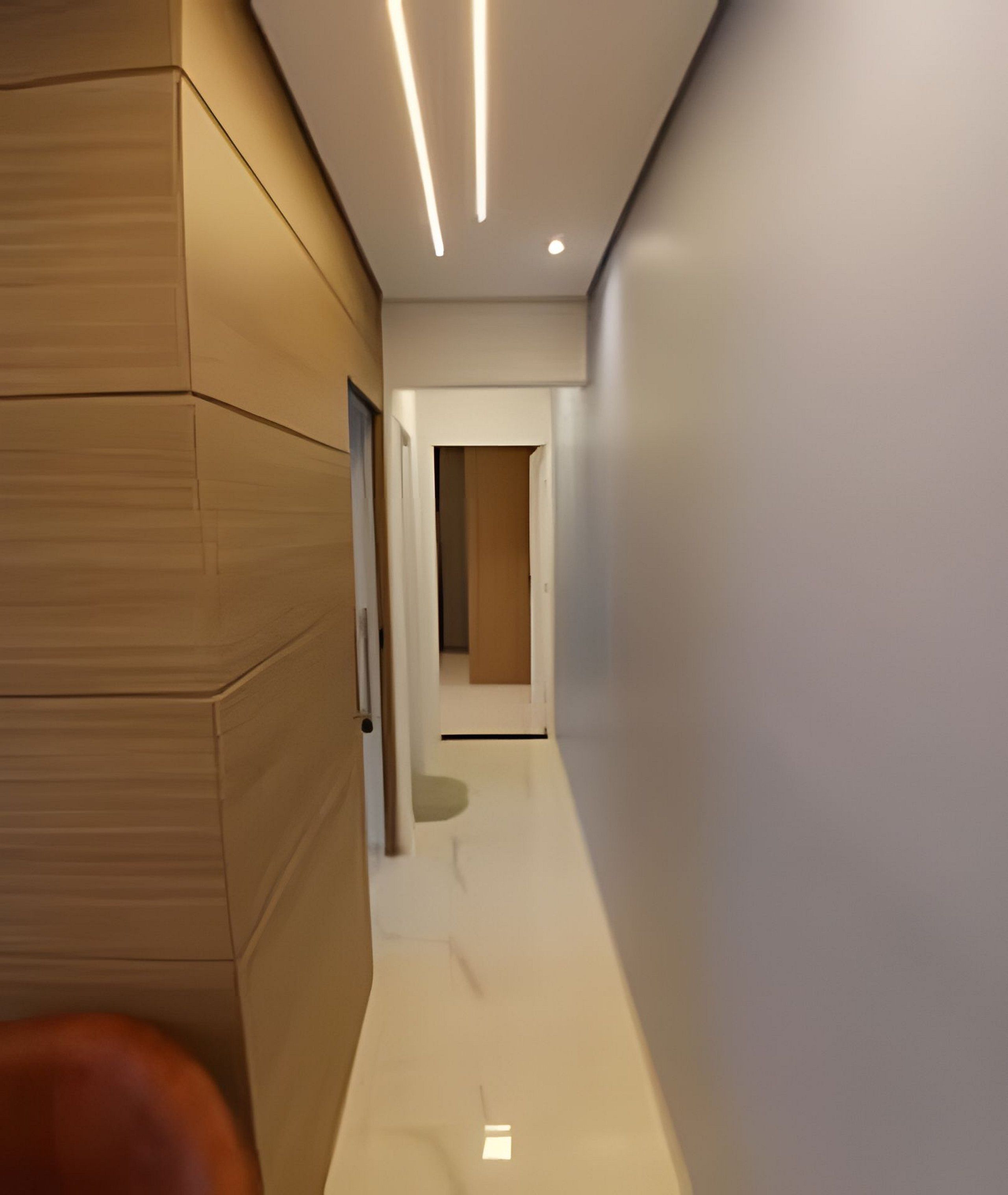 A modern hallway with wooden paneling on one side, a glossy white floor, and recessed lighting.