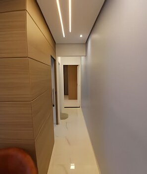 A modern hallway with wooden paneling on one side, a glossy white floor, and recessed lighting. - SHB - Família - Moderno - Ferry Boat (Santos)