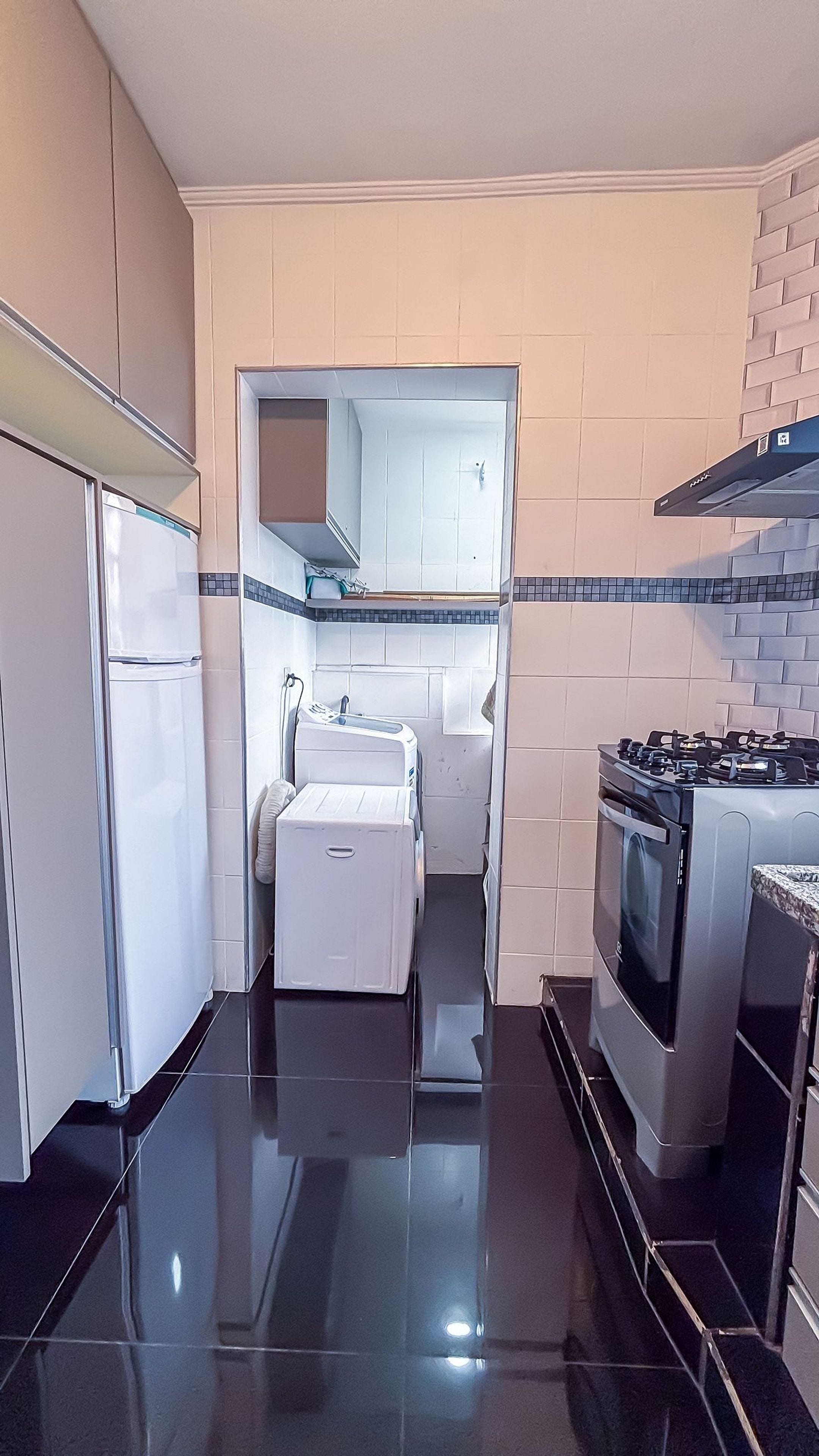 A kitchen with a refrigerator, washing machine, stove, and tiled backsplash.