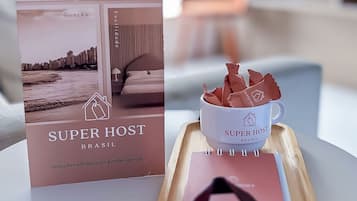 Un folleto titulado 'SUPERHOST BRASIL' con imágenes de un interior moderno, una taza de café y un cuaderno sobre una mesa.