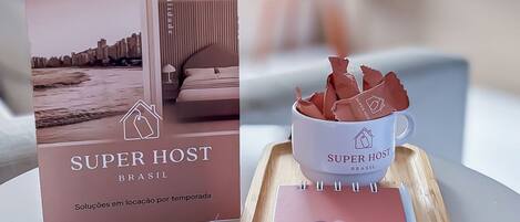 A brochure titled 'SUPERHOST BRASIL' with images of a modern interior, a cup of coffee, and a notebook on a table.