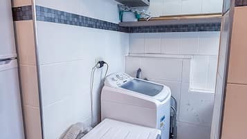 A compact laundry room with a washing machine, dryer, and a small countertop.