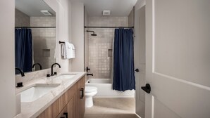 Un bagno moderno con un mobile lavabo doppio, una vasca da bagno e un water.