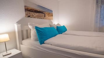 Et soveværelse med en seng, et natbord, en lampe og et maleri på væggen.