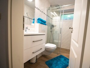Un baño moderno con inodoro, lavamanos y zona de ducha.