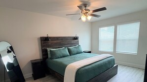 A bedroom with a bed, a ceiling fan, a dresser, and a window with blinds. - Fresh Townhome in Pensacola (Pensacola)