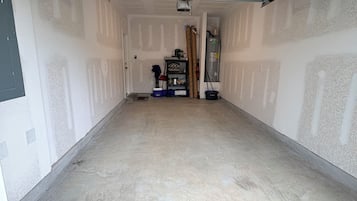 Eine Garage mit Betonboden, einer Tür und einem Regal mit verschiedenen Gegenständen.