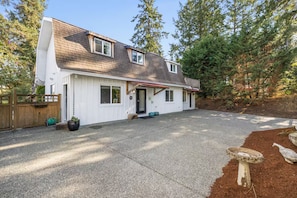 A two-story house with a sloped roof, a front porch, and a driveway leading to the garage. - Amazing 2-bedroom cottage in Victoria, perfect for relaxing getaways. (Victoria)