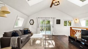 Een ruime woonkamer met een hoge plafond, een bank, een salontafel en een televisie.