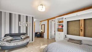 Een slaapkamer met een bed, een bank, een kledingkast en een spiegel.