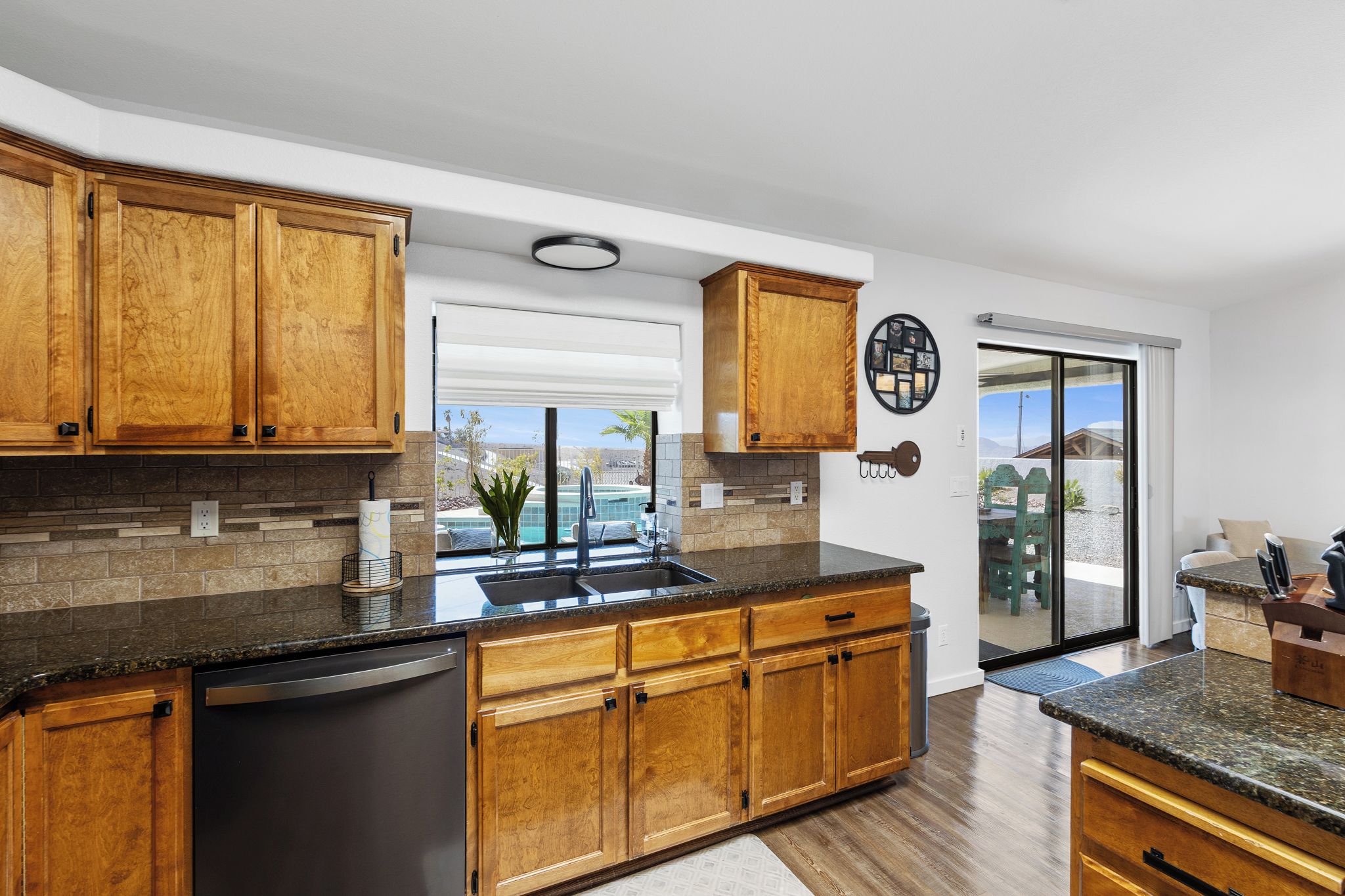 A modern kitchen with wooden cabinets, a granite countertop, and a built-in dishwasher.