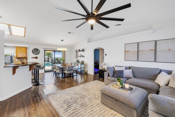 Ein geräumiger Wohnbereich mit Deckenventilator, einem Esstisch und einer Couch.